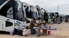 Sudanese drivers rest next to their vehicles after transporting evacuees from Sudan into Egypt, in Wadi Karkar village near Aswan