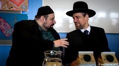 Imam Ramazan Demir (left) and rabbi Schlomo Hofmeister speak in front more than 150 students crowding a hallway at AHS Franklin High School in Vienna, Austria