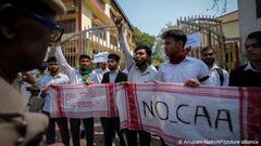 Male students hold up red and white cloths with the words 'No CAA' during a protest against the Citizenship Amendment Act (CAA) in Guwahati, India, 12 March 2024