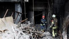 Two firefighters stand at the scene of a fire that broke out at a nightclub in the basement of a 16-story building in the Besiktas district of Istanbul, Turkey, 2 April 2024