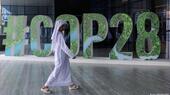Eine Person in arabischer Kleidung geht an einem "#COP28"-Schild in Abu Dhabi, Vereinigte Arabische Emirate, vorbei