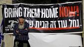 A man stands next to a banner demanding in English and Hebrew the release of Israeli hostages held by Hamas