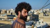 Man with a full head of hair and beard photgraphed against the skyline of Beirut