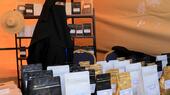 A woman wearing a black hijab and face veil displays products at a fair organised to promote locally grown coffee in Sanaa, Yemen, 3 March 2024