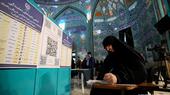 A woman holds a pen in her hand as she looks at a ballot paper at a polling station in Iran