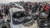 Palestinians inspect a burnt car after an Israeli airstrike, which resulted in numerous deaths and injuries