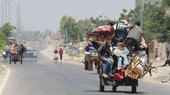 Young people in Gaza sit on a cart loaded with furniture and other belongings and leave the destroyed city