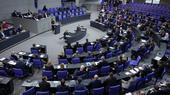 Annalena Baerbock stands at a podium in the centre giving a speech to a crowd of seated people wearing suits.