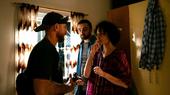 Two men and a woman stand in a room and talk to each other