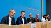 Sieben Männer und Frauen sitzen als Sprecher:innen im Raum der Bundespressekonferenz
