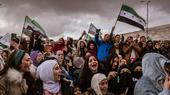Women and men at a demonstration in Syria with the flag of the revolution