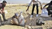 A man pulls a bag from a hole in the ground.