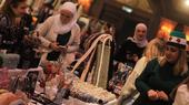 A group of women stand around a table upon which a number of handicrafts are placed for sale.