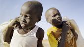 Two young boys carrying bags over their shoulders.