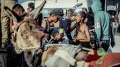 صبي يأكل المعكرونة النيئة بينما يحمل فلسطينيون مساعدات إنسانية.
