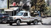 Ein Pickup-Wagen mit aufgesetzter Waffe, dahinter ein Mann.