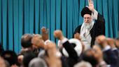 علي خامنئي يقف أمام حشد من المستمعين ويرفع يده اليسرى.