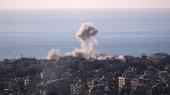 A plume of smoke rises from a building in a dense Beirut neighbourhood. The sea and the sky are in the background.