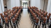 Clay sculptures of heads are arranged in rows in a gallery.