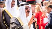 أمير الكويت، الذي يرتدي ثوباً طويلاً ومنديل رأس أبيض، يحيي الحشد.