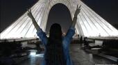 فتاة كاشفة الرأس تقف أمام برج آزادي في طهران تظهر علامة النصر بكلتا يديها  نوفمبر  / تشرين الثاني 2022 - إيران.