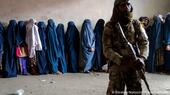 أحد أعضاء حركة طالبان يحرس نساء مصطفات للحصول على إمدادات إغاثة.