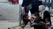 Eine Mutter sitzt mit ihre Kinder in einem Flüchtlingslager in Gaza