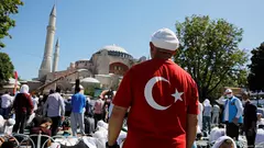 Man stands in front of the Hagia Sophia, his back to the camera, wearing a Turkish flag t-shirt