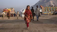 An Afghan refugee girl collects rubbish in a camp near the Pakistan-Afghanistan border in Torkham