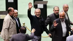 Iran's President Pezeshkian, surrounded by members of the parliament, waving and laughing