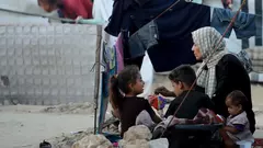 Eine Mutter sitzt mit ihre Kinder in einem Flüchtlingslager in Gaza