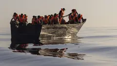 Menschen mit Schwimmwesten, die von Freiwilligen der Ocean Viking, einem von den Nichtregierungsorganisationen SOS Mediterranee und der Internationalen Föderation des Roten Kreuzes (IFCR) betriebenen Such- und Rettungsschiff für Migranten, zur Verfügung gestellt wurden, fahren in einem Holzboot, 27. August 2022, südlich der italienischen Insel Lampedusa im Mittelmeer (Foto: picture alliance / ASSOCIATED PRESS | Jeremias Gonzalez)