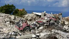 Landscape, destroyed houses and vehicles. The Mediterranean Sea in the background.