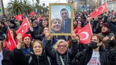 Women protest with Turkish flags. One holds a picture of herself and Ekrem İmamoğlu.