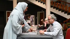 Jan Dost signiert sein Buch, eine Frau mit Hijab steht vor ihm.