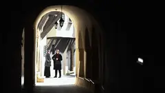 Zwei Frauen stehen in einem Torbogen in der Sonne und schauen in den Schatten.