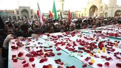 Trauerumzug mit Särgen in iranischen Flaggen, auf ihnen liegen Rosenblätter