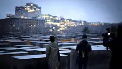 Tourists photograph the Holocaust Memorial in Berlin on a winter evening.