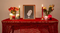 بورتريه لشابة محجبة وبجواره شموع وباقة ورود على منضدة.  