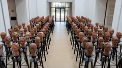 In einer Galerie sind Tonfiguren von Köpfen in Reihen angeordnet.