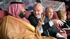 ولي العهد السعودي الأمير محمد بن سلمان آل سعود، ورئيس الاتحاد الدولي لكرة القدم (فيفا) جياني إنفانتينو، والرئيس الروسي فلاديمير بوتين (من اليسار إلى اليمين) في حفل افتتاح كأس العالم 2018 في ملعب "لوجنيكي" بموسكو، روسيا، في 14 يونيو/حزيران 2018.