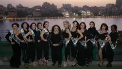12 Frauen stehen eng beieinander und schauen in die Kamera, sie tragen alle schwarze Kleidung. Im Hintergrund sieht man den Nil in Kairo und Lichter.