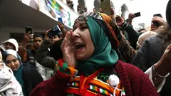 تظهر امرأة أمازيغية ترتدي زيًا تقليديًا وحُلياً تراثية، فيما يوثق الحاضرون المشهد بهواتفهم.
