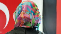 Woman with headscarf, a Turkish and a German national flag in the background (photo: picture-alliance/dpa)