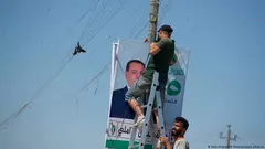 Men place an election poster for the upcoming early parliamentary elections on 10 October near private generator network wires in Baghdad.