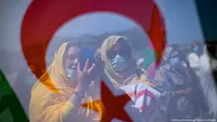 محتجتان صحراويتان تنظران من خلال العلم الصحراوي أثناء مشاركتهما في مسيرة لدعم إبراهيم غالي زعيم جبهة البوليساريو - شمال إسبانيا - الأحد  30 مايو / أيار 2021.