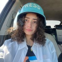 Plestia Alaqad sitzt in einem Auto und trägt einen Schutzhelm mit der Aufschrift „Press“.