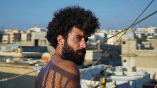 Man with a full head of hair and beard photgraphed against the skyline of Beirut