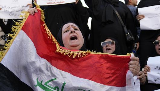 Iraqi women protesting, front one holding Iraqi flag