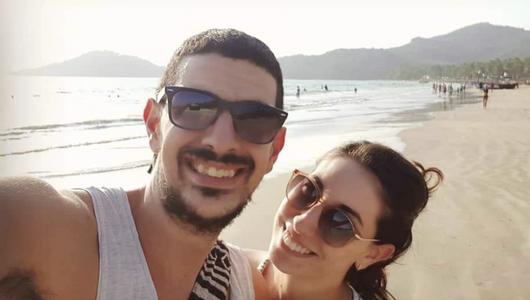 Selfie of a couple at the beach. They wear sunglasses.